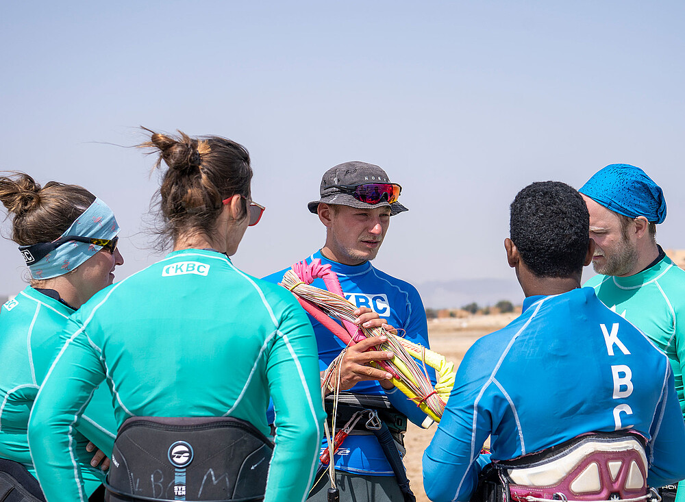 EG kitesurfing instructeur legt kite-equipment uit aan groep kitesurfers op strand - kitesurfing lessen watersport