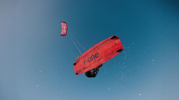 Kitesurfer F-ONE kiteboarding met Bandit Kite in de lucht, spectaculaire sprong tijdens watersport in het KBC Wereldnetwerk