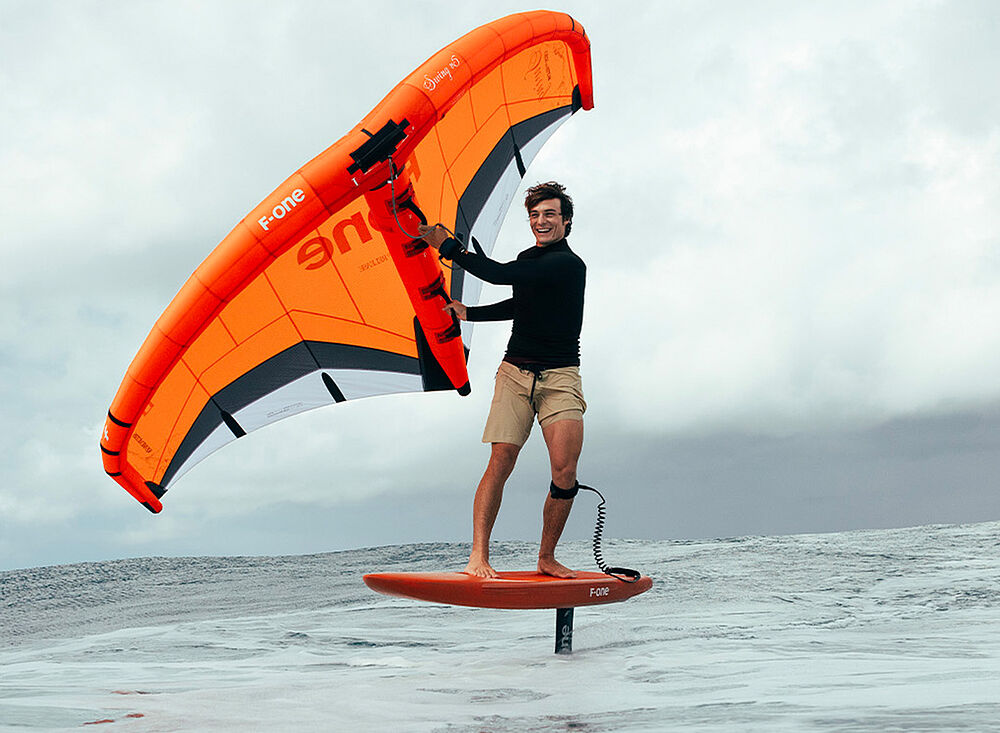 Kitesurf Holland003 auf Hydrofoil-Board mit orangem Kite über dem Meer - Kitesurfing Wassersport Holland