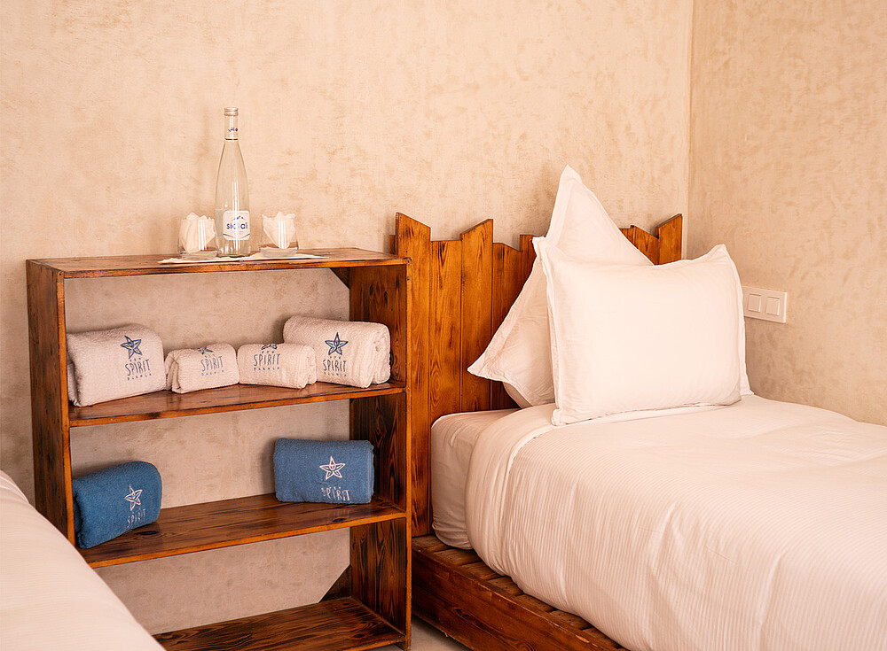 NewSpiritDakhla Standard Bungalow bedroom with wooden furniture and towels - kiteboarding accommodation Dakhla
