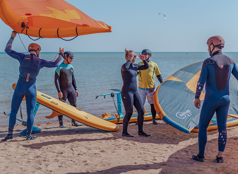 Wingfoil Event op strand - kitesurfers in wetsuits met kites en boards bij watersport