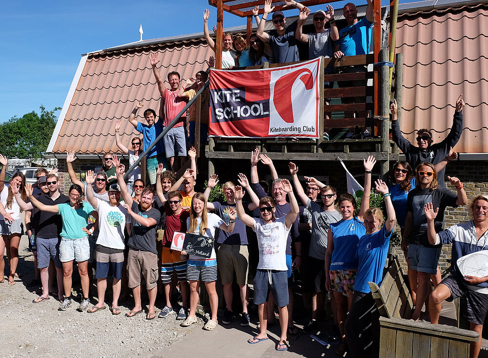 Kitesurf Holland012 Kiteboarding Schule Gruppe Foto - Glückliche Kitesurfer winken am Strand in Holland Wassersport