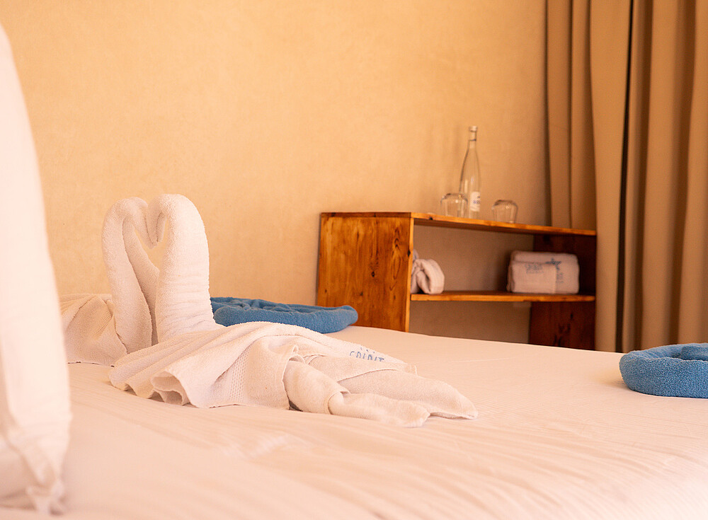 NewSpiritDakhla Bungalow Deluxe hotel room with bed and blue towels - kiteboarding accommodation Dakhla Morocco