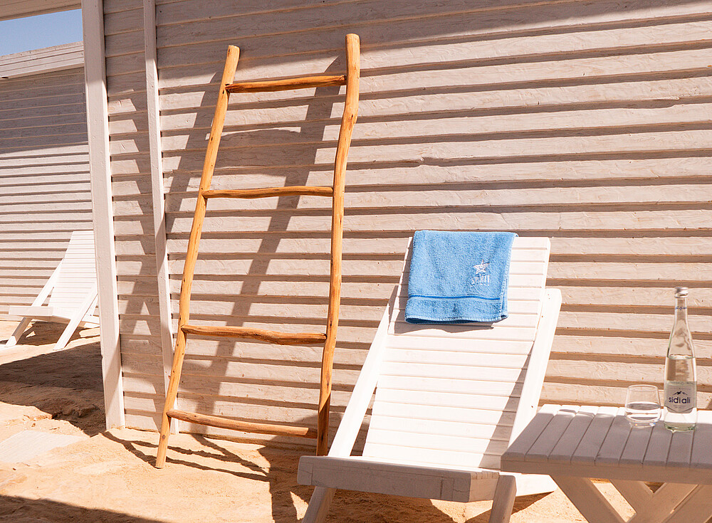 Luxury Deluxe bungalow at NewSpiritDakhla with wooden ladder, beach chair and blue towel - perfect kiteboarding accommodation