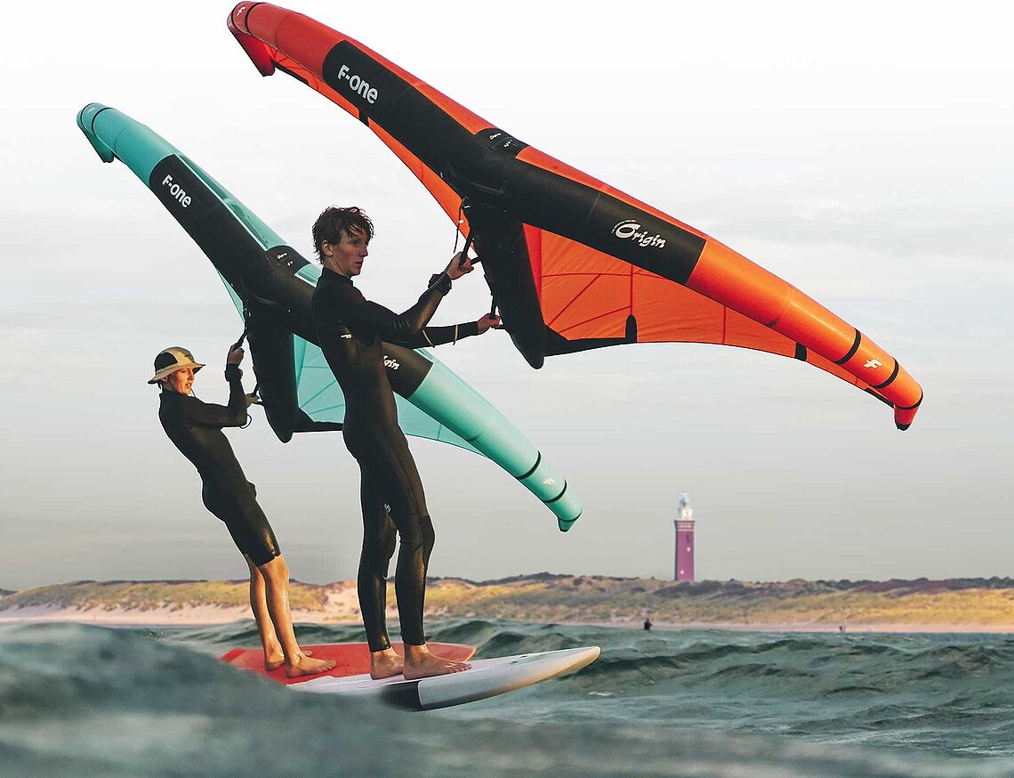 Kitesurfing at KBC Brouwersdam: Two kitesurfers with F-ONE kites on the water in front of the lighthouse in Holland