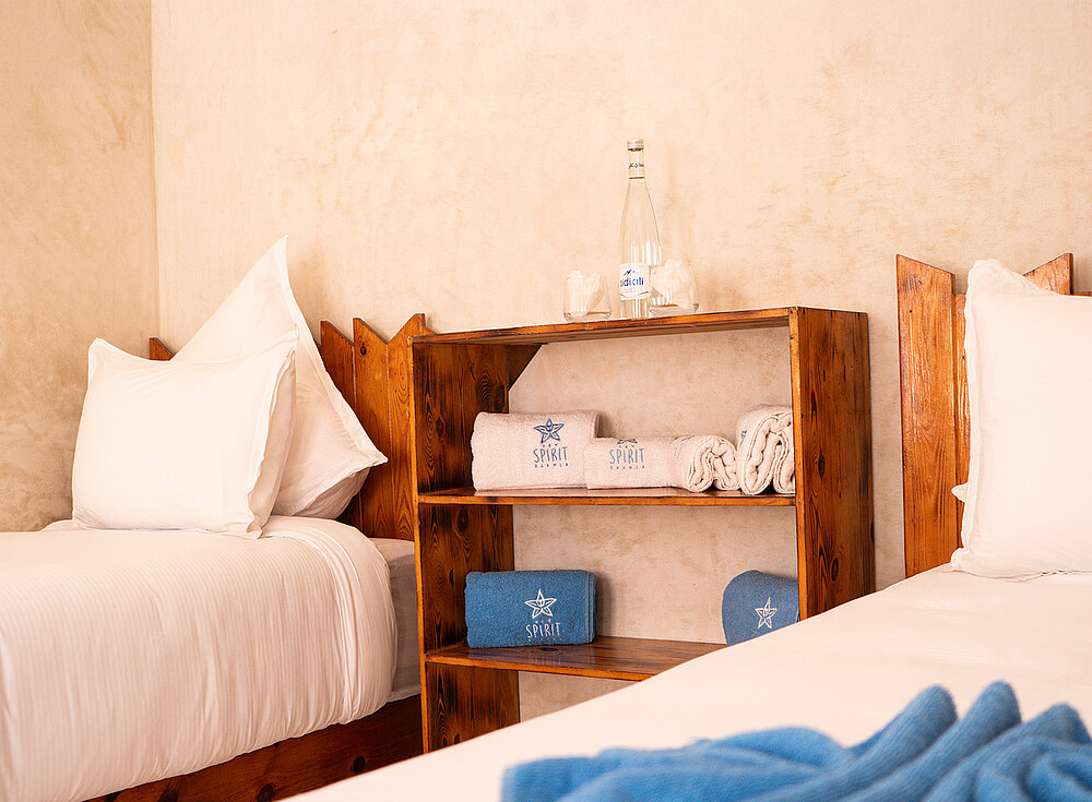 NewSpiritDakhla Standard Bungalow bedroom with white bedding and towels - kiteboarding accommodation in Dakhla