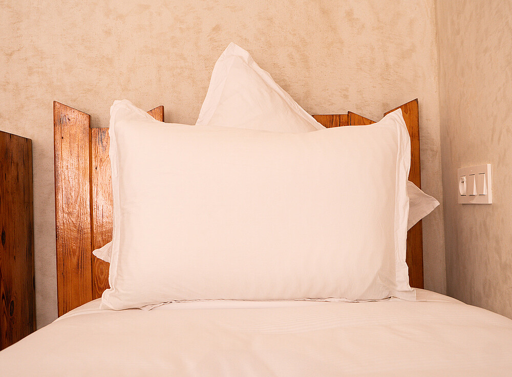 NewSpiritDakhla Standard Bungalow bedroom with white pillows and wooden headboard - kiteboarding accommodation Dakhla