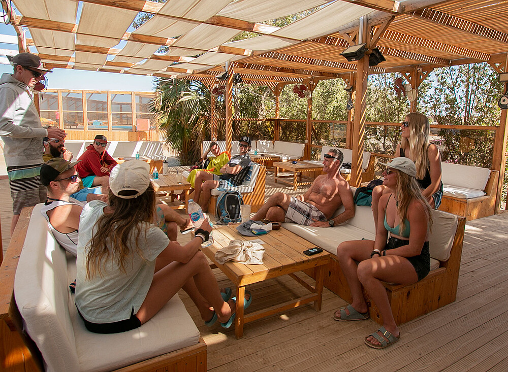 EG Life kitesurfing groep ontspant op houten terras bij strand kiteboarding reisbestemming