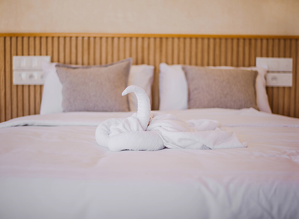 Premium Bungalow bedroom at NewSpiritDakhla kiteboarding resort with decorative towel swans on white bed
