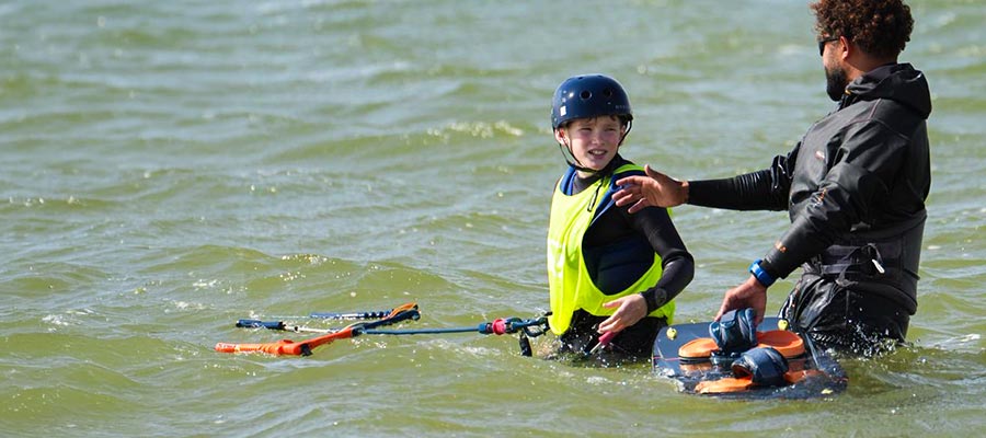 Dakhla kitesurfcursus kinderen - kite-instructeur leert kind in het water op het strand, KBC Dakhla kiteschool Marokko