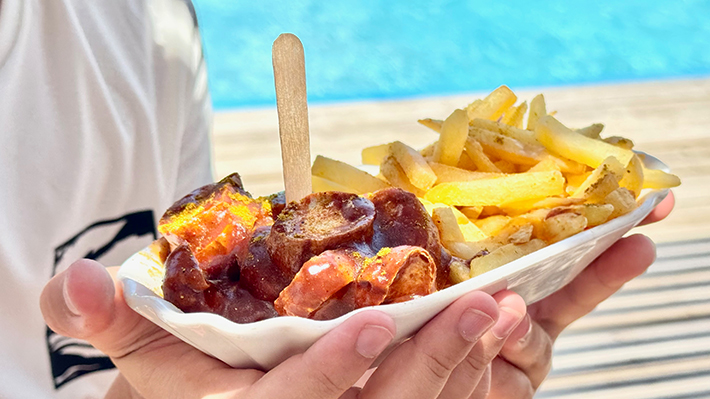 Belly eet Currywurst op het strand bij KBC El Gouna - perfecte versterking na het kitesurfen in Egypte