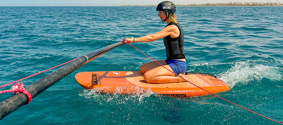 Foilsimulator beim Kitesurfen auf orangem Board im türkisblauen Wasser - Kiteboarding Wassersport am Strand