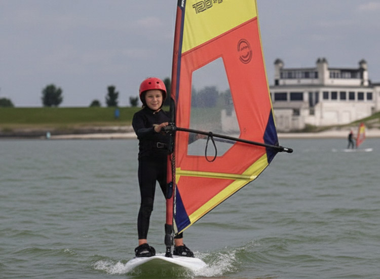 Windsurfen kids cursus bij KBC Hindeloopen - Kind met windsurf zeil op het water tijdens watersport in Nederland