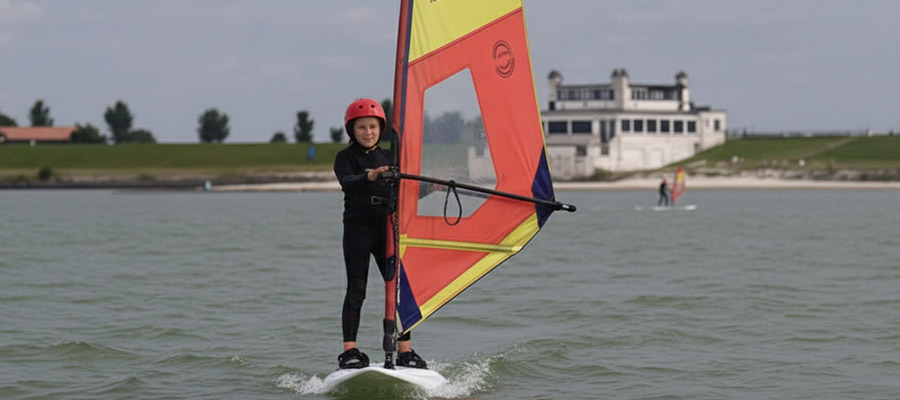 Windsurf Kids KBC Hindeloopen - Jovem windsurfista com vela colorida na água na escola de Kitesurf da Holanda