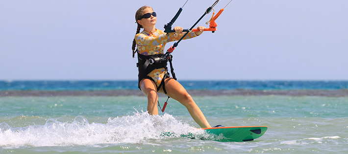 Kitekurs Kids - Jonge kitesurfer aan het kiteboarden op turquoise strandwater, watersport reisbestemming