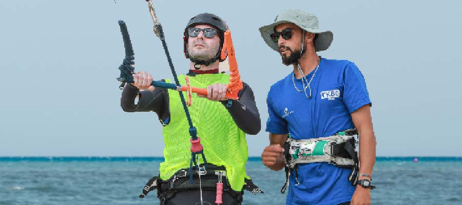 IKO kitesurfing beginner course at Kiteboarding Club KBC Limnos - instructor and student on beach with kite gear