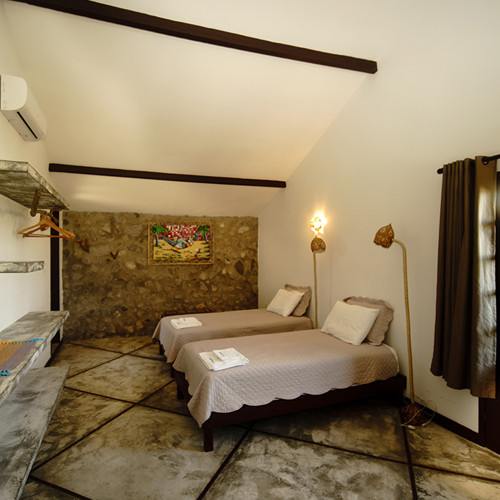 Quarto duplo aconchegante com parede de pedra no KBC Kitesurf Center Parajuru - hospedagem ideal para kitesurfistas