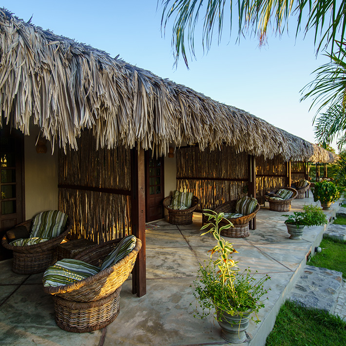 Acomodação tropical com teto de palha no KBC Parajuru - centro de kitesurf no Brasil com jardim e móveis lounge