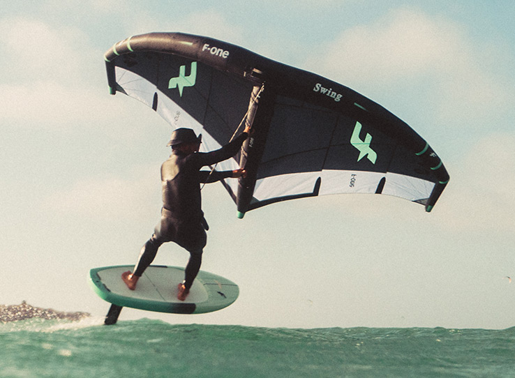Wingfoil kitesurfer jumping over turquoise waters at Kiteboarding Club KBC Sal Surf Hub, Cape Verde water sports