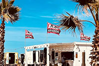 KBC Kitesurf Center Sizilien Lo Stagnone met News en Spirit bij wit gebouw met palmbomen onder blauwe hemel