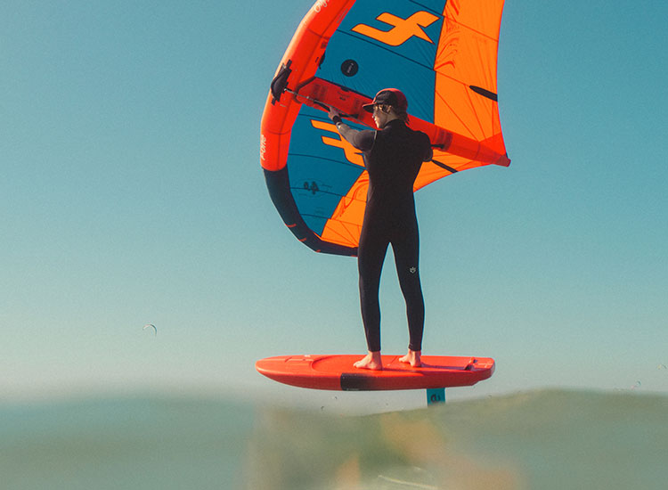Kitesurfer with orange-blue kite on board at Kiteboarding Club KBC Sizilien - ideal kitesurfing conditions