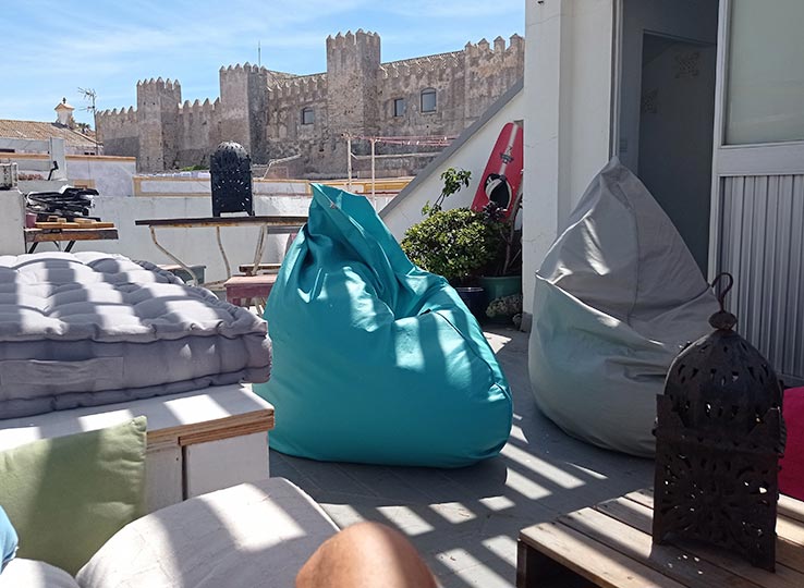 Terraço relaxante no Kiteboarding Club KBC Tarifa com puffs coloridos e vista do castelo - Espanha