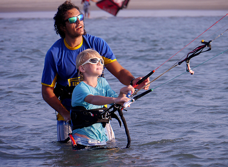 Kitesurfles met Kitesurfkurs - instructeur leert kind kitesurfen in water, watersport les op strand