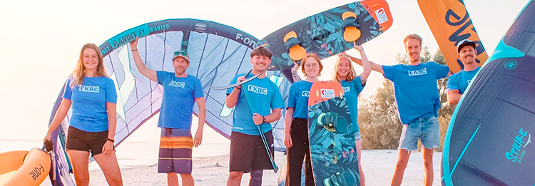 Vrolijke kitesurfing groep op strand met kites en boards - watersport reisbestemming voor kiteboarding vakanties
