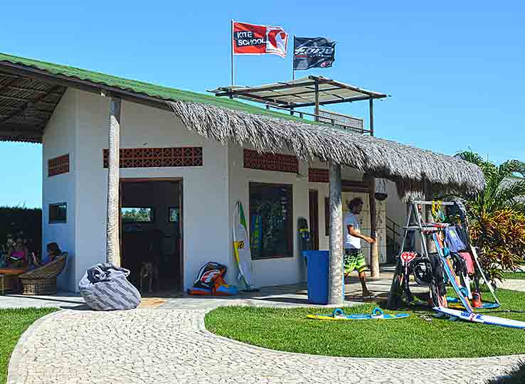 Kiteboarding shop with palm roof at tropical beach destination - kitesurf equipment and gear outside white building