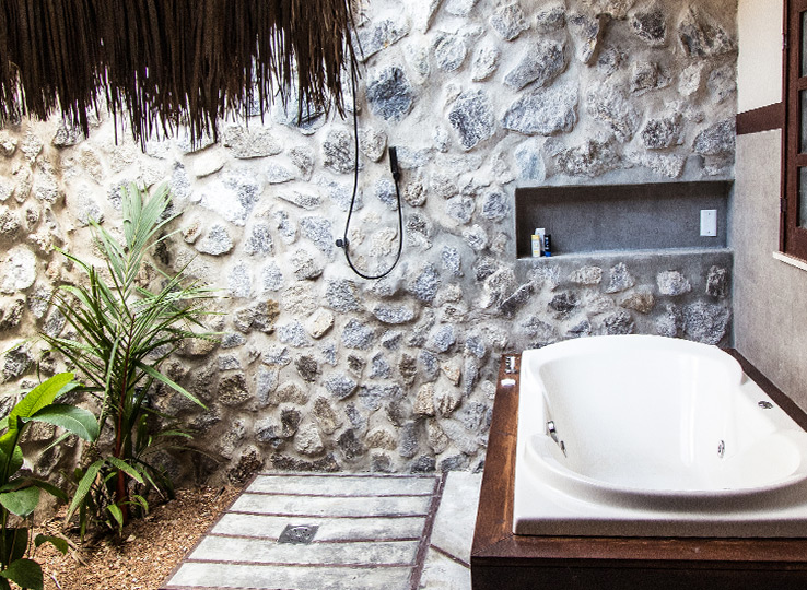 Luxury tropical bathroom with stone wall and jacuzzi tub - perfect relaxation after kiteboarding at beach destination