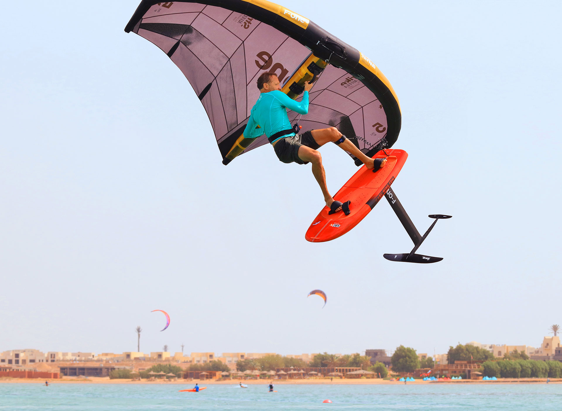 Wingfoil Event - Kitesurfer springt met wingfoil-board boven turkooizen water op strand, watersport reisbestemming